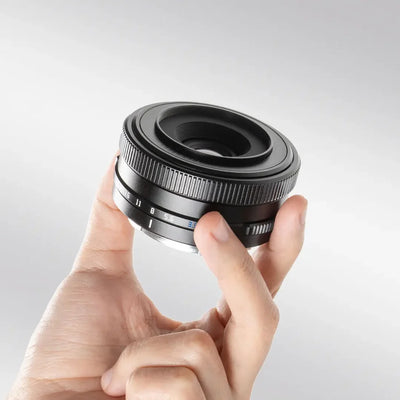 TTArtisan AF 14mm f/3.5 pancake lens held in hand, front angle