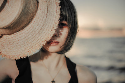Close portrait of a woman half hidden by a straw hat, f/1.2 sample from the Voigtlander Nokton 40mm