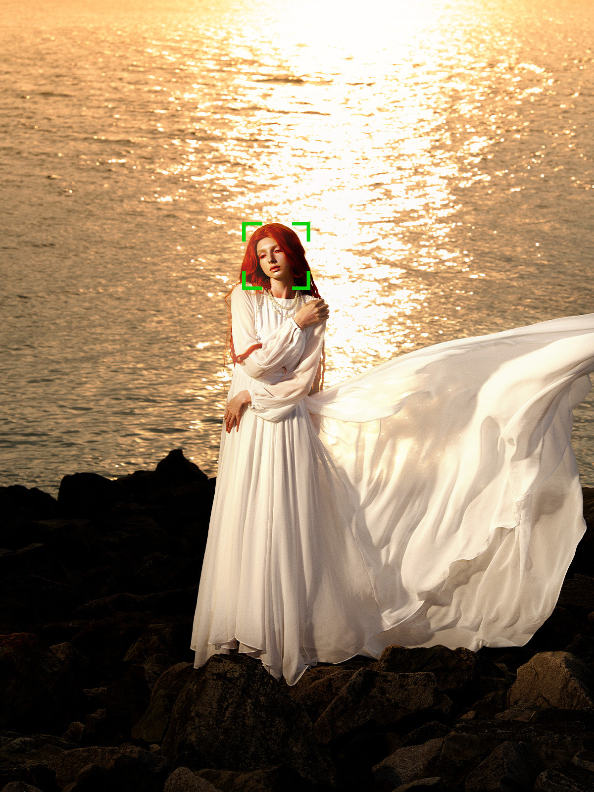 Woman in a flowing white dress on rocks at sunset, eye autofocus sample from the Viltrox 85mm f/1.4 Pro