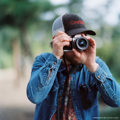 Man in a CineStill cap taking a photo with a Nikon film camera, CineStill 400D sample