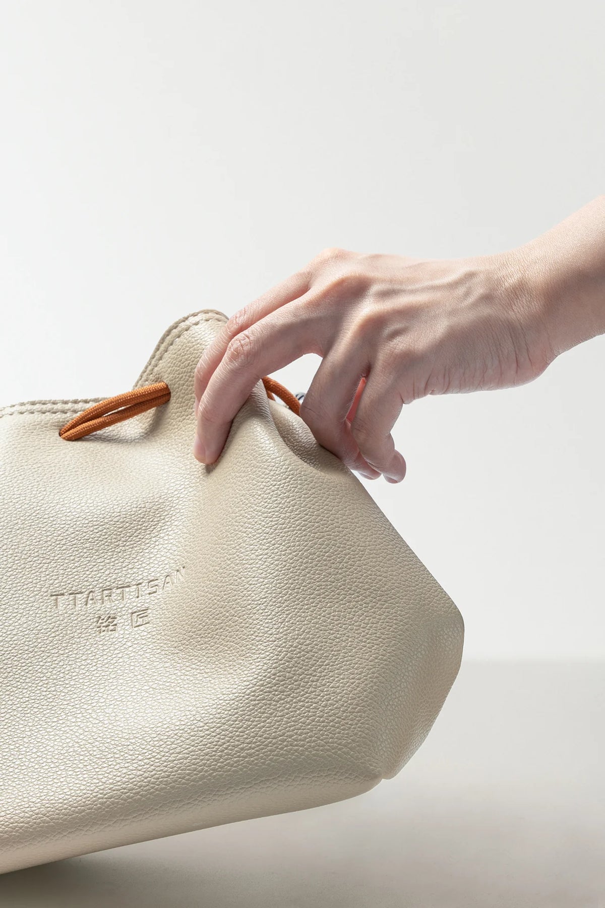 Hand opening the TTArtisan cream drawstring bag