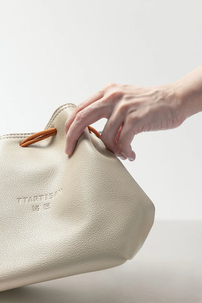 Hand opening the TTArtisan cream drawstring bag