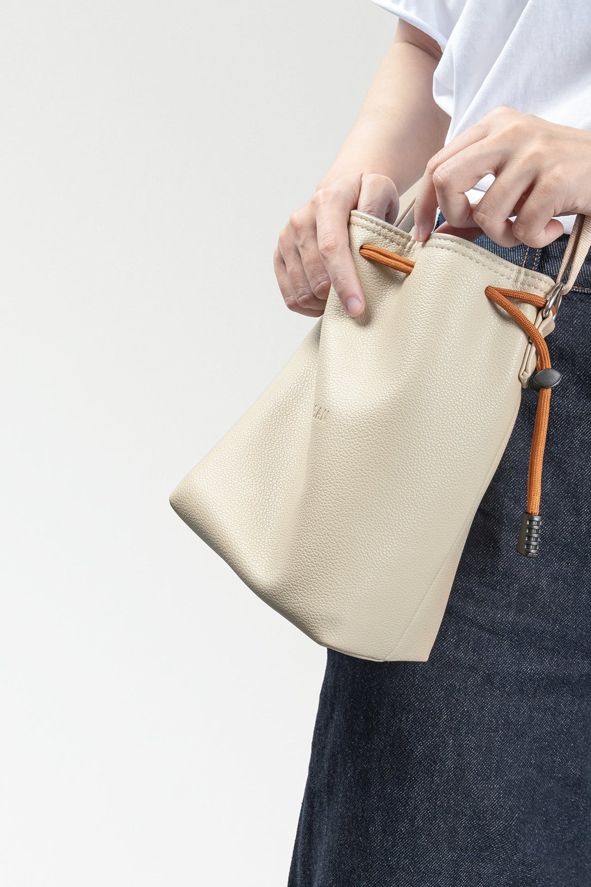 Woman wearing the TTArtisan cream drawstring bag at her hip