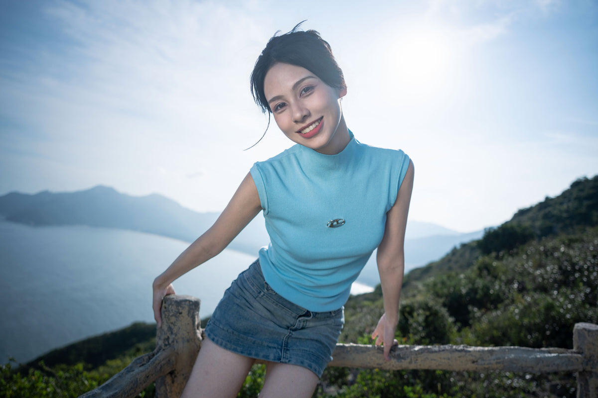 Smiling woman by a wooden fence above the sea, sample from the Viltrox 15mm f/1.7