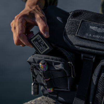 Hand putting a battery into a Wotancraft Armor small pocket on a black bag