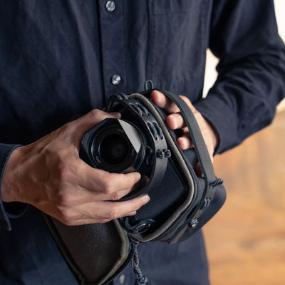 Hands taking a camera out of the Wotancraft black canvas pouch