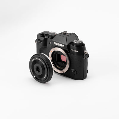 Viltrox AF 28mm f/4.5 XF pancake next to a black Fujifilm X-T50 body