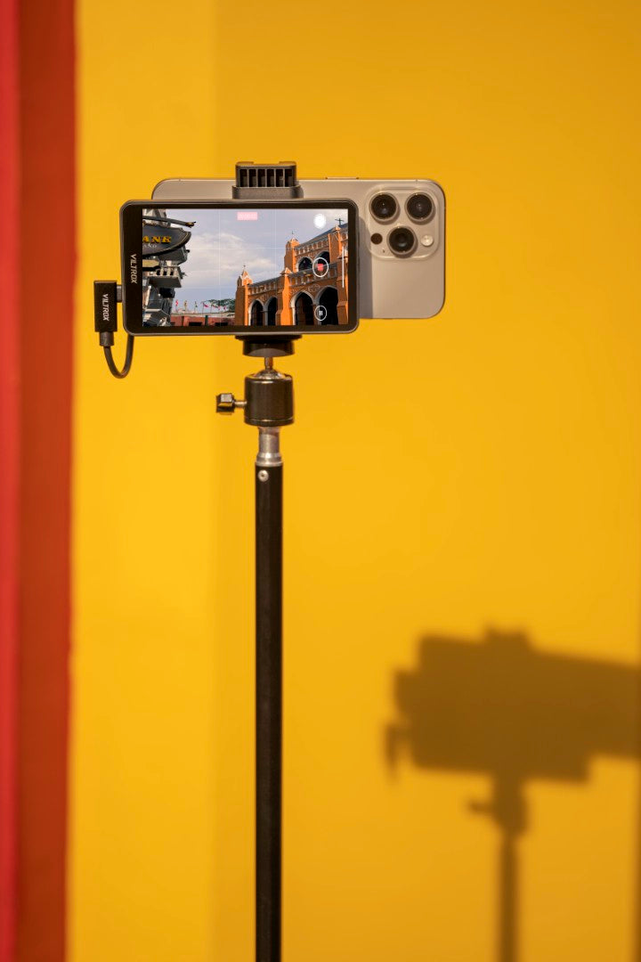 Viltrox DC-T1 monitor clipped to an iPhone on a light stand against a yellow wall