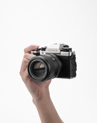 Viltrox AF 75mm f/1.8 XF mounted on a silver Fujifilm X-T5 held in hand