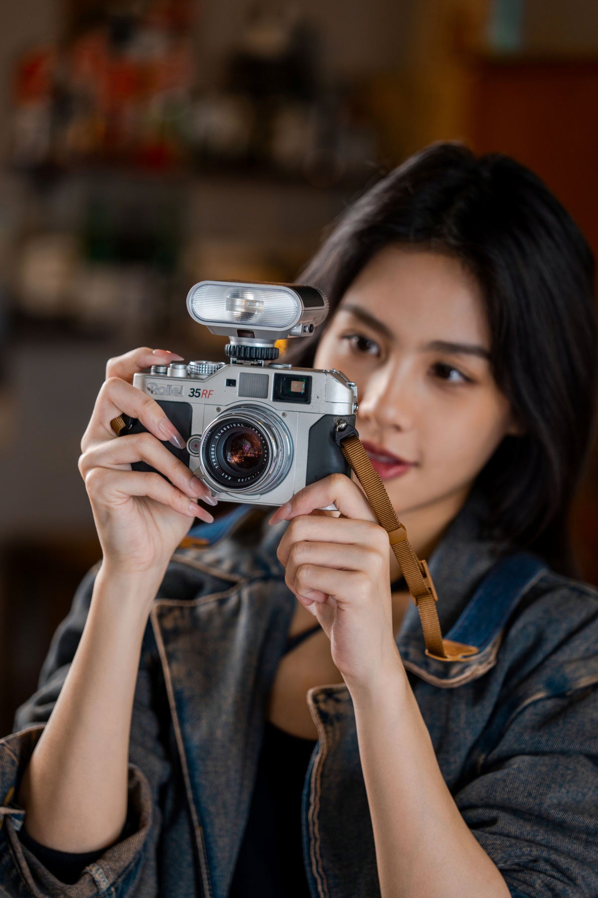Woman holding a silver Rollei 35 RF camera with the Viltrox Vintage Z1+ flash