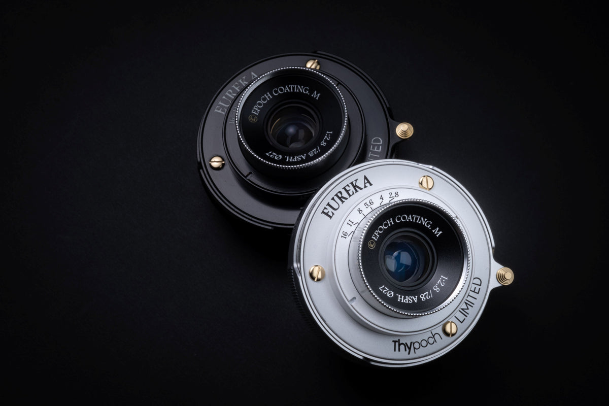 Thypoch Eureka 28mm f/2.8 ASPH pancake lenses in black and silver side by side