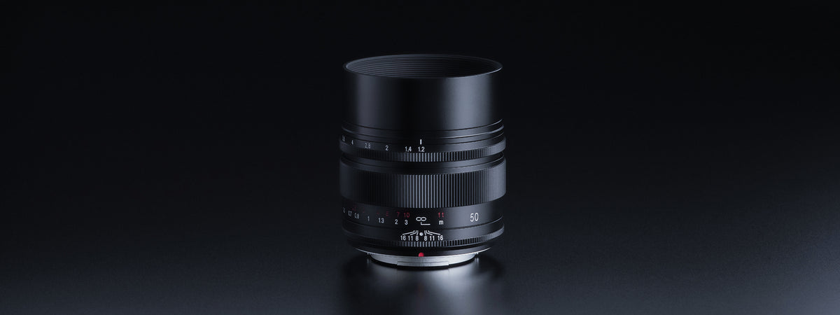 Voigtlander Nokton 50mm f/1.2 Fuji X lens with hood on a dark background