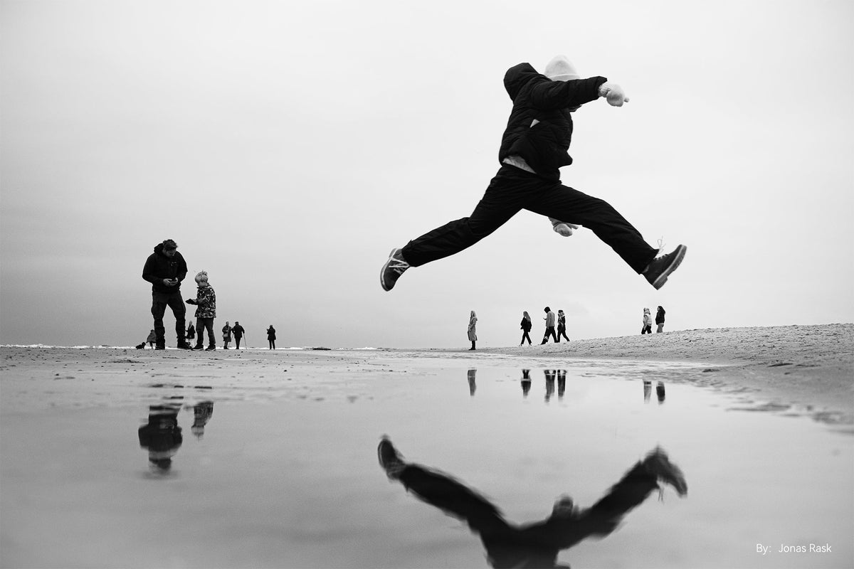 Boy jumping over a puddle on the beach in black and white, TTArtisan AF 27mm f/2.8 sample