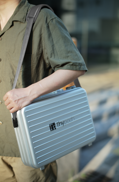 Person carrying the silver Thypoch aluminium lens case on a shoulder strap