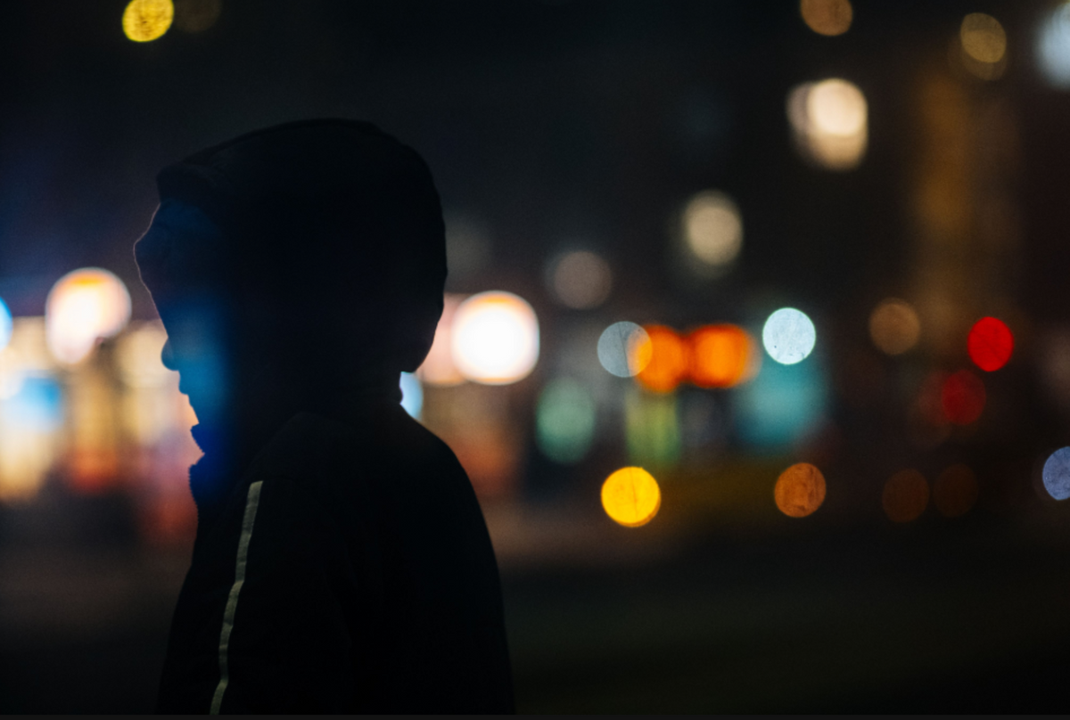 Silhouette of a person in a hood with colourful city bokeh, sample from the Thypoch Simera 75mm