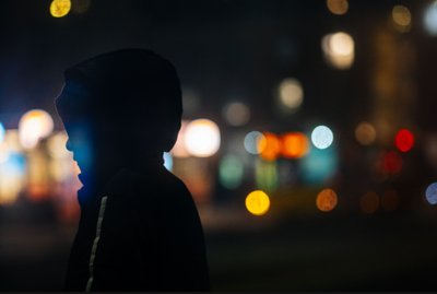 Silhouette of a person in a hood with colourful city bokeh, sample from the Thypoch Simera 75mm