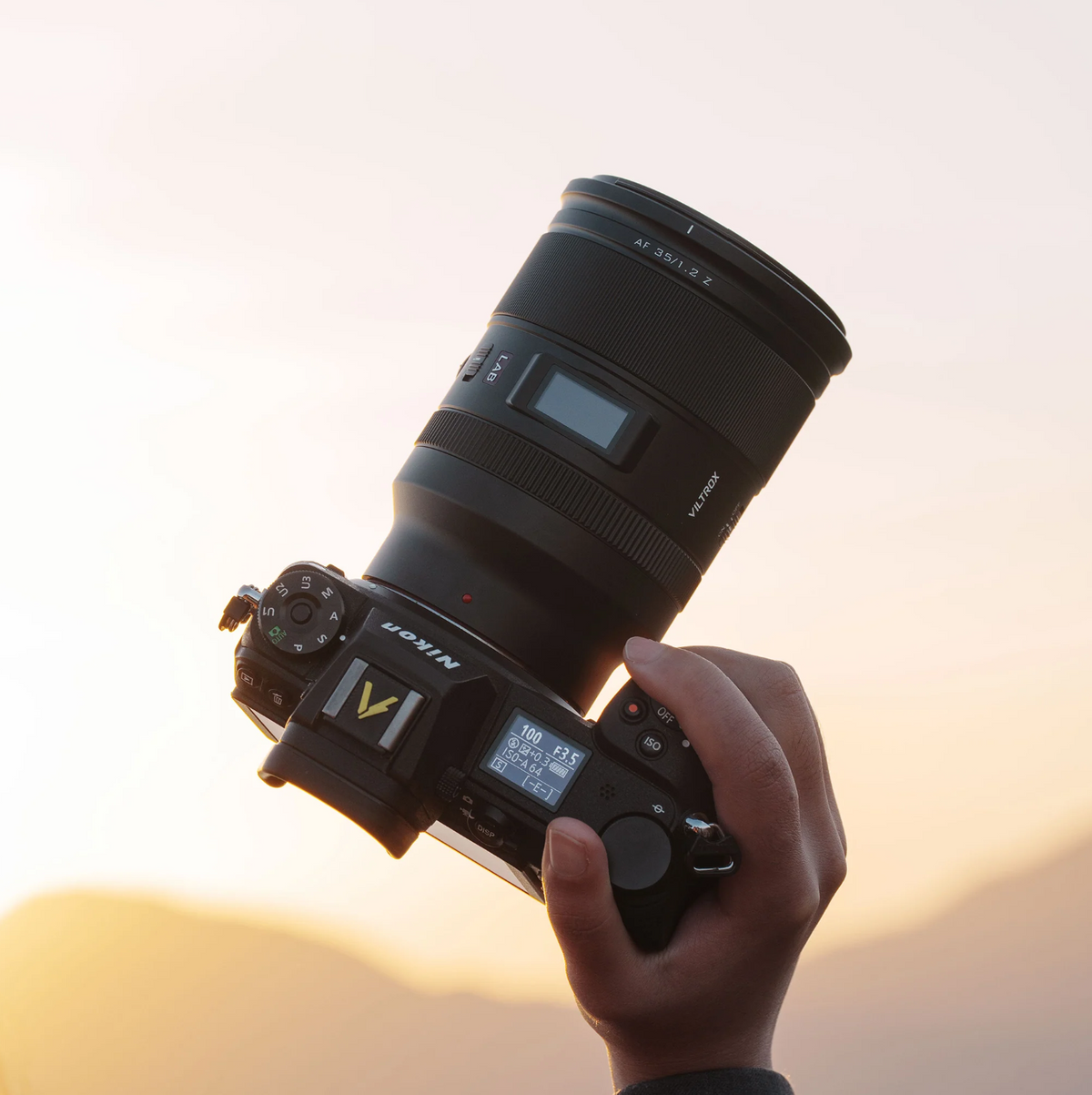 Viltrox LAB 35mm f/1.2 on a Nikon Z camera held up against a sunset sky