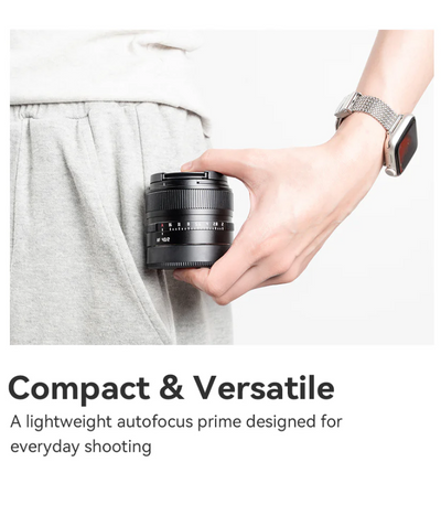 TTArtisan AF 40mm f/2 compact lens held in one hand next to a trouser pocket