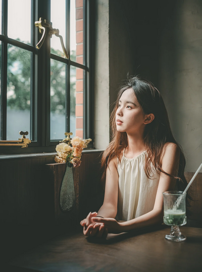Woman by a cafe window with flowers, portrait sample from the TTArtisan AF 40mm f/2