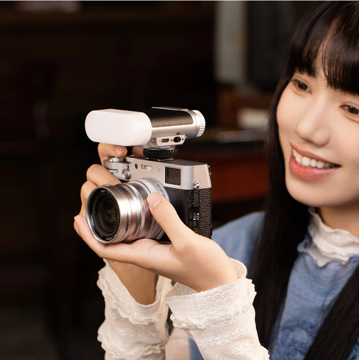 Woman holding a silver Fujifilm X100 with the Viltrox Vintage Z1 flash on top