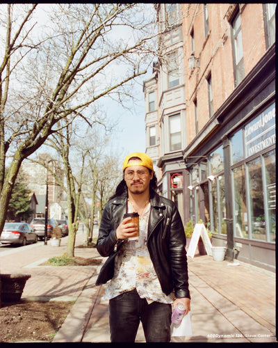 Man in a yellow cap with coffee on a city street, sample shot on CineStill 400D