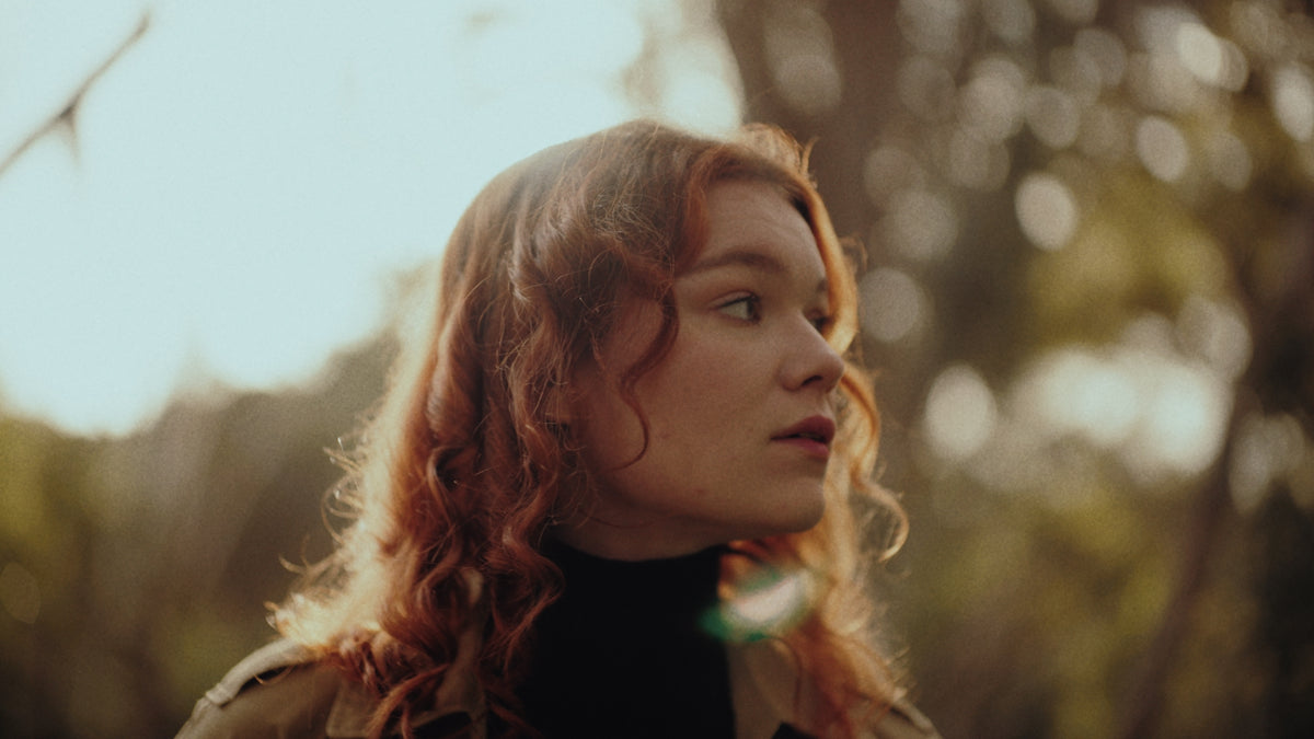 Woman with red hair in a forest, shallow depth of field sample from the Thypoch Simera-C cine lenses