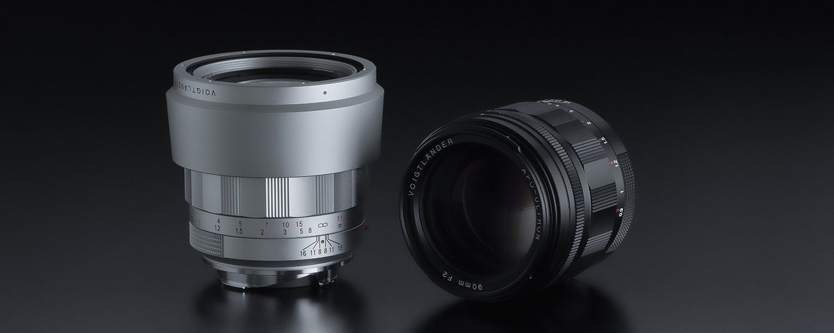 Voigtlander APO-Ultron 90mm f/2 VM in silver with hood next to a black version