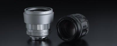 Voigtlander APO-Ultron 90mm f/2 VM in silver with hood next to a black version