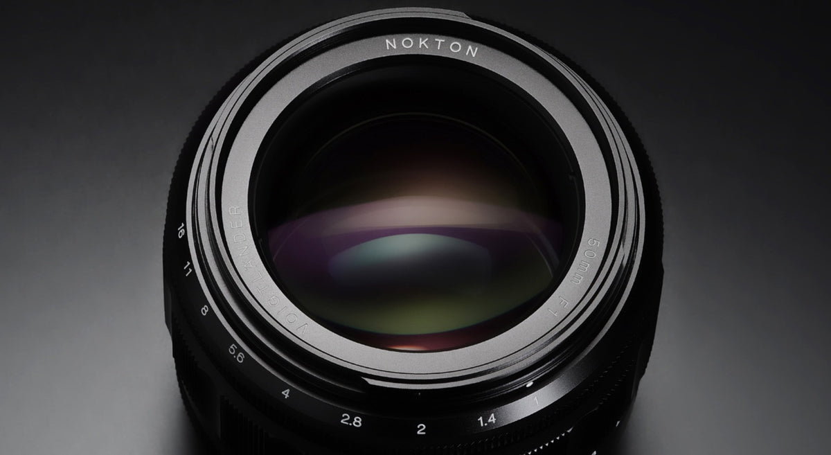 Voigtlander Nokton 50mm f/1.0 front element with multi-coating on a dark background