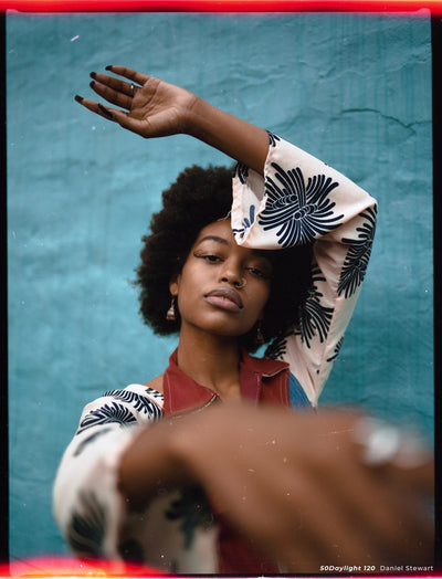 Woman raising her arm against a teal wall, sample shot on CineStill 50D 120