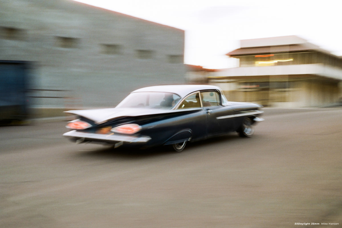 Classic car driving past a building, sample shot on CineStill 50D