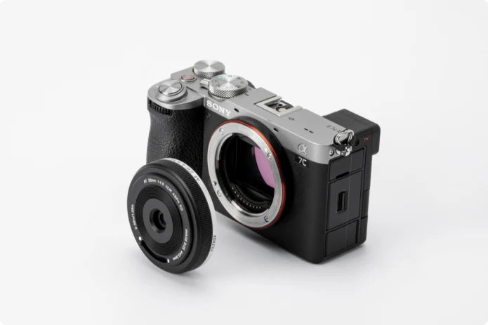 Viltrox AF 28mm f/4.5 FE pancake lens beside a silver Sony A7C II