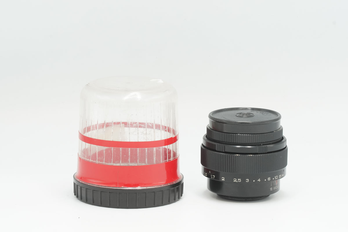 Jupiter-9 85mm f/2 black lens next to its original plastic case