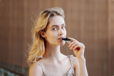 Woman holding the Viltrox AF 28mm f/4.5 pancake lens to her lips to show how thin it is