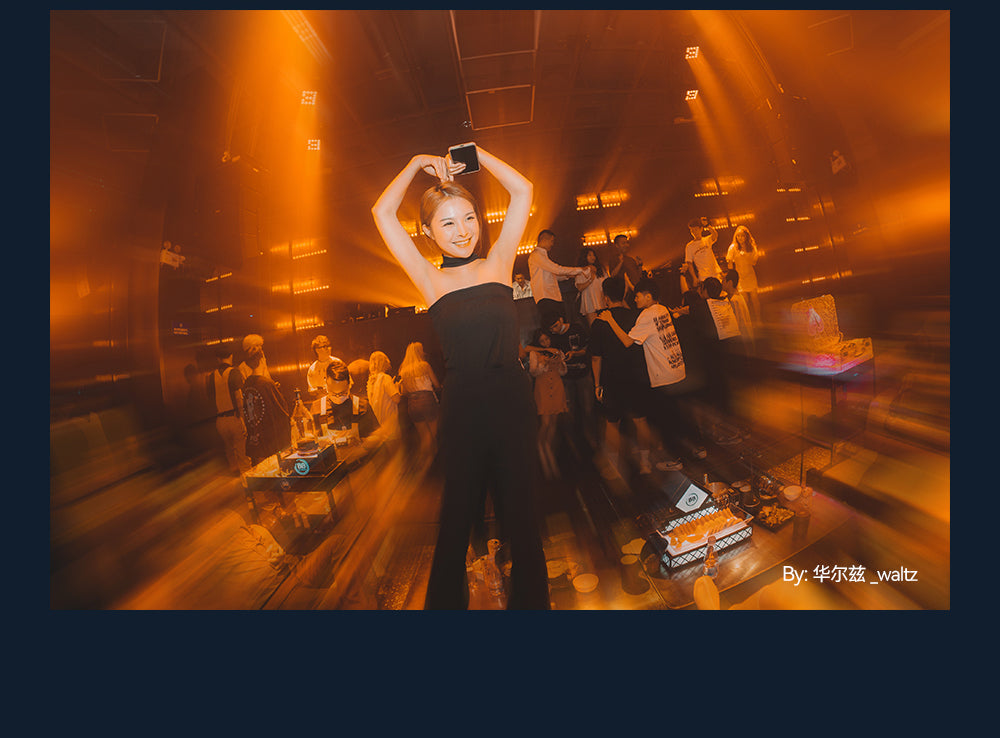 Woman dancing at a party with orange light, fisheye sample from the TTArtisan 7.5mm f/2
