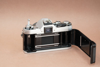 Canon AE-1 film camera with the back open, showing the film chamber