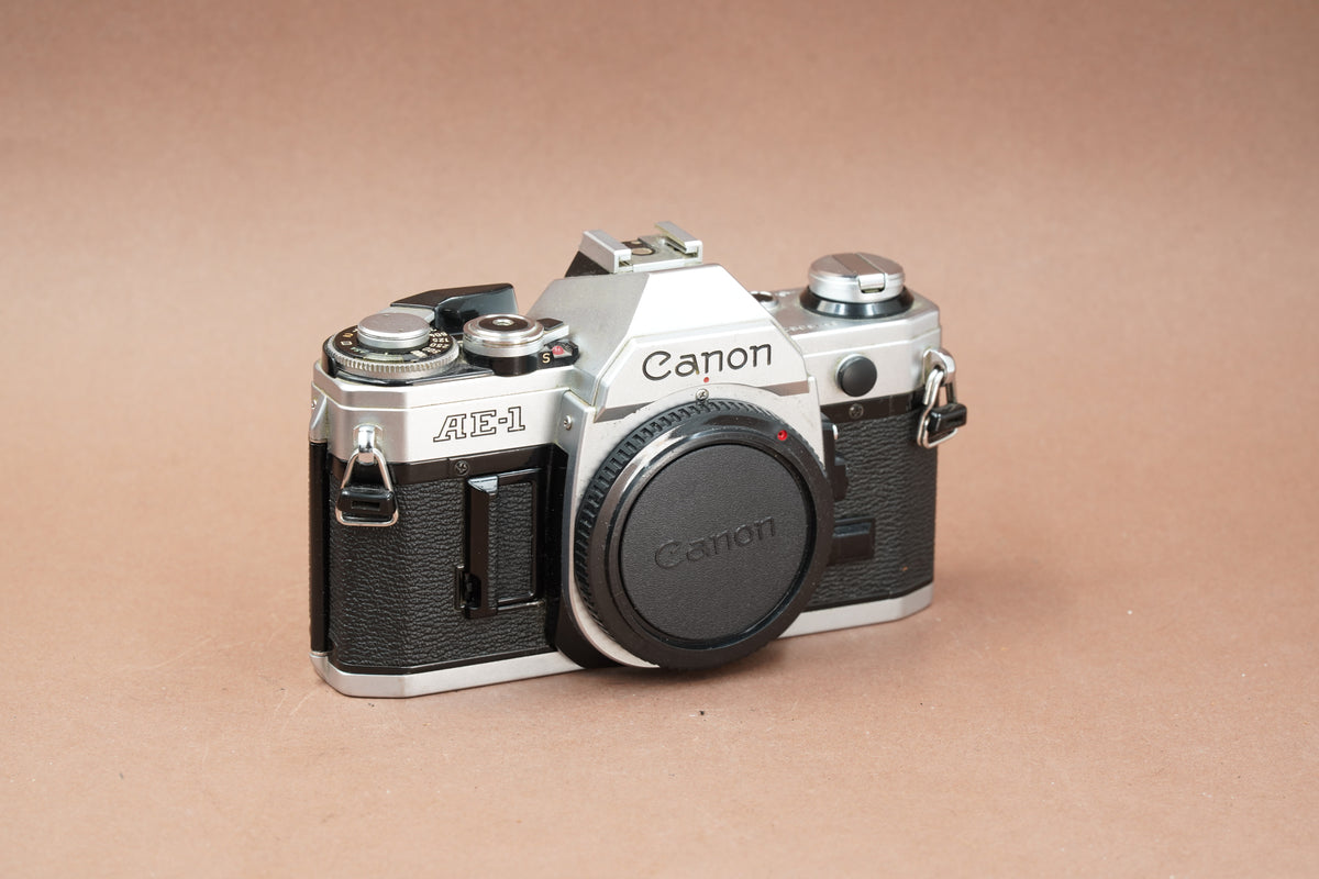Canon AE-1 35mm SLR film camera in silver and black with body cap